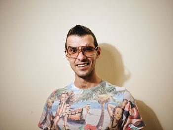 Portrait of young man wearing sunglasses while standing against wall