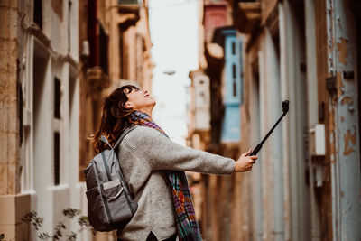 Side view of woman holding monopod standing in alley