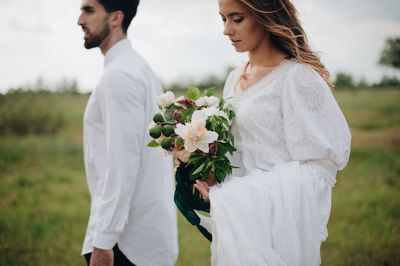 Bride and bridegroom standing on field