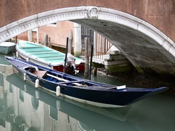 Boats moored in canal by arch bridge