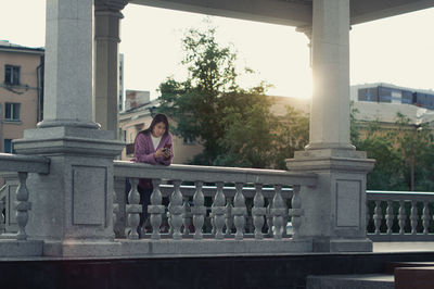 Portrait of woman standing against railing