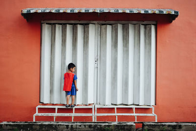 Boy standing against red wall
