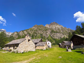 Built structure on field by houses against sky