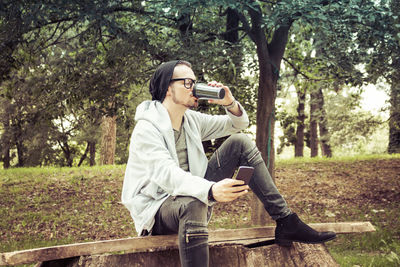 Man photographing with camera while sitting on tree