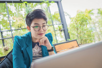 Mid adult man using mobile phone while sitting on window