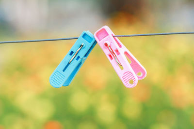 Close-up of clothespins hanging on rope against blurred background