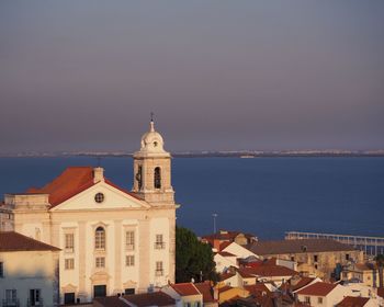 Church in town by sea against sky