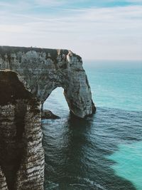 Rock formation by sea against sky