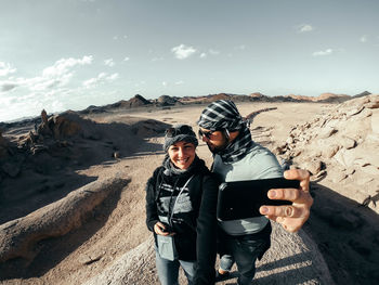 Full length of man photographing on mountain against sky