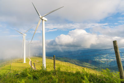 Windmills on field against sky