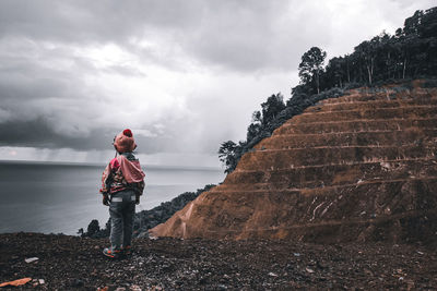 Man standing by wall against sky