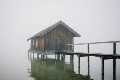 Wooden house by lake against clear sky