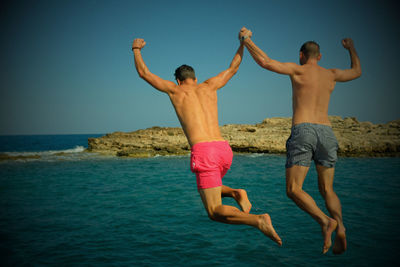 Full length of shirtless boy in sea against sky