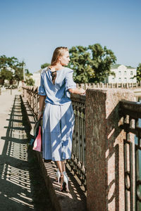 Full length of woman standing by railing against sky