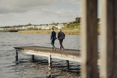 Two businessmen walking on jetty at a lake