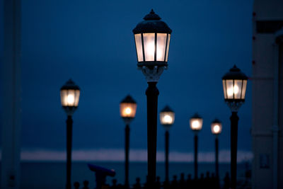 Illuminated street light against blue sky at night