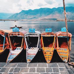 Boats moored on sea by mountains against sky