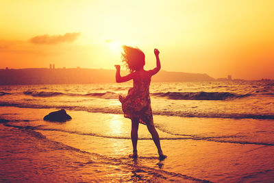 Woman standing on beach during sunset