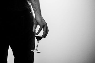 Midsection of man holding wineglass against white background