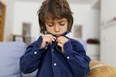 Little boy buttoning his shirt