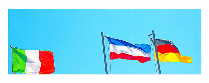 Low angle view of flag flags against clear blue sky