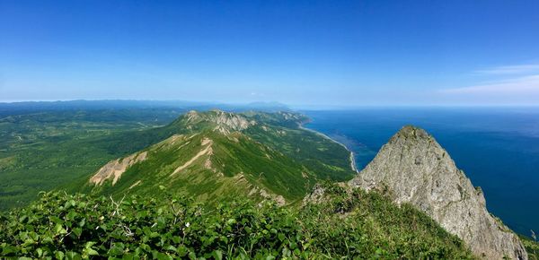 Scenic view of sea and mountains against blue sky