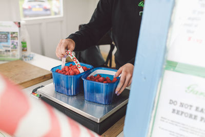 Midsection of woman in front of strawberries on weight scale in store