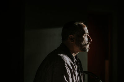 Side view of man standing against black background