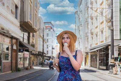 Portrait of young woman standing on street in city