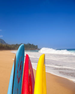 Close-up of multi colored deck chairs on beach against clear blue sky