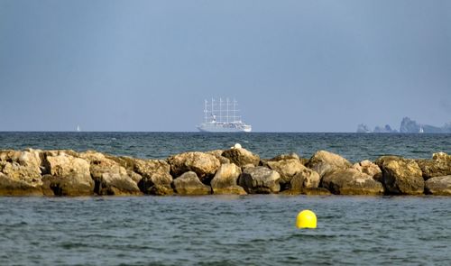 Sailboat on rock by sea against clear sky