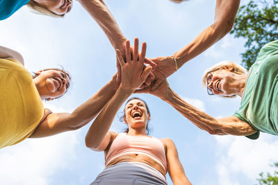 Low angle view of woman with arms raised against sky