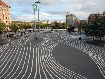 Road by buildings in city against sky
