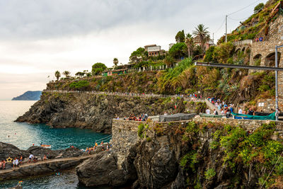 People on rock by sea against sky