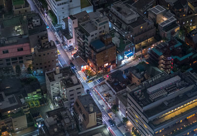 High angle view of illuminated street amidst buildings in city at night