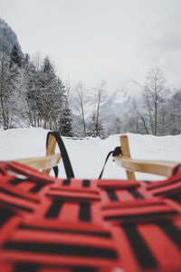 Sled on snow covered field against sky