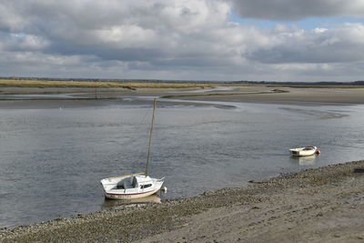 Sailboats moored on sea against sky