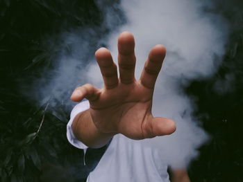 Midsection of man reaching from amidst smoke