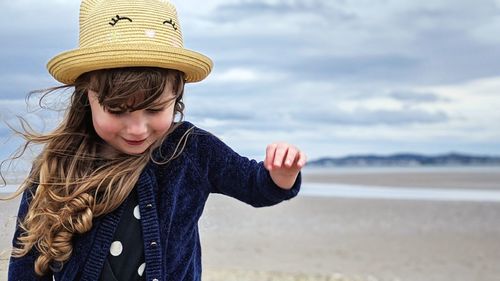 Boy wearing hat at beach against sky