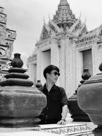 Smiling man looking away while standing outside temple building