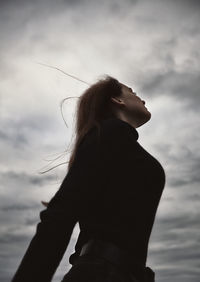 Low angle view of woman standing against sky during sunset