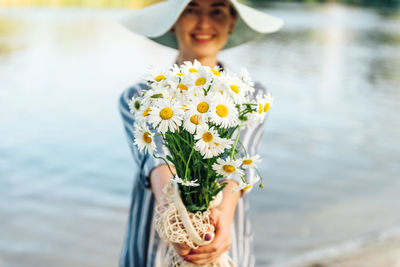 Midsection of woman holding flower against blurred background