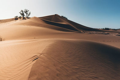 Sand dunes in desert against clear sky