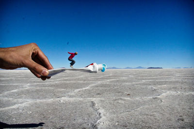 Optical illusion of woman jumping on toothpaste held by man at salar de uyuni