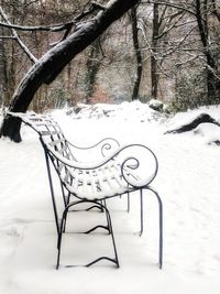 Empty bench in snow covered park during winter