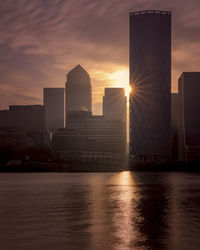 Modern buildings in city against sky during sunset