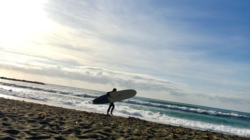 Man surfing on beach against sky