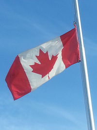 Low angle view of flags flag against clear blue sky