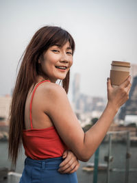 Portrait of a smiling young woman holding camera