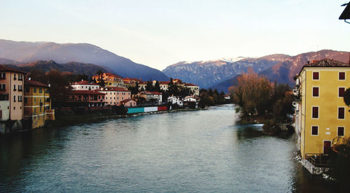 Buildings by river against sky in town